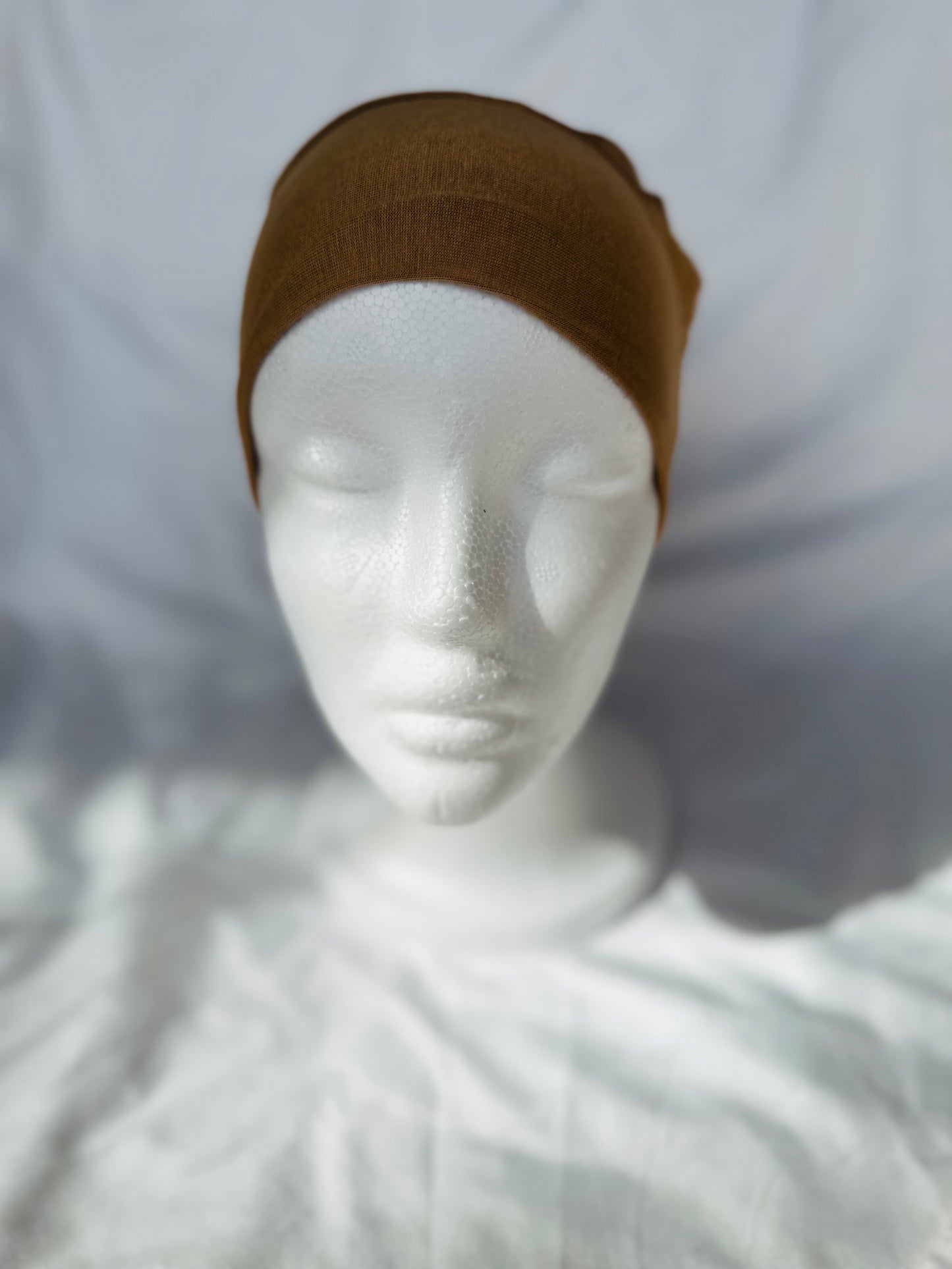 Lightweight jersey undercap - perfect for everyday hijab wear Tan hijab undercap displayed on soft fabric, highlighting its neutral color and breathable texture designed for everyday wear.

