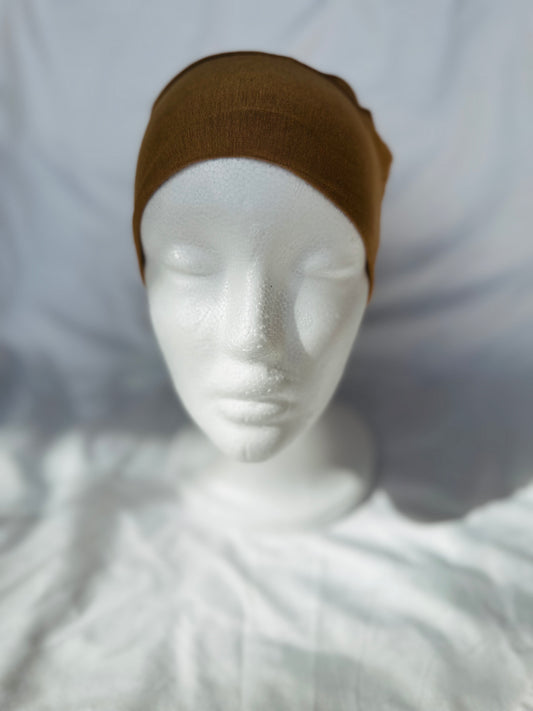 Lightweight jersey undercap - perfect for everyday hijab wear Tan hijab undercap displayed on soft fabric, highlighting its neutral color and breathable texture designed for everyday wear.

