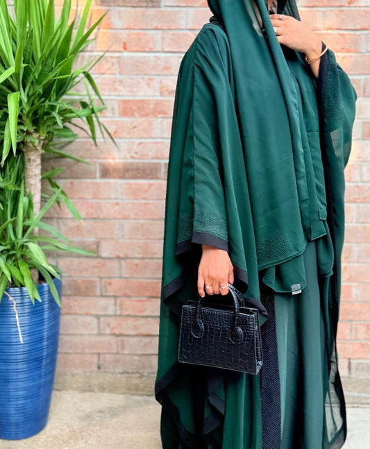 Model wearing Mina Emerald Green Abaya with Black Borders in a modest relaxed silhouette